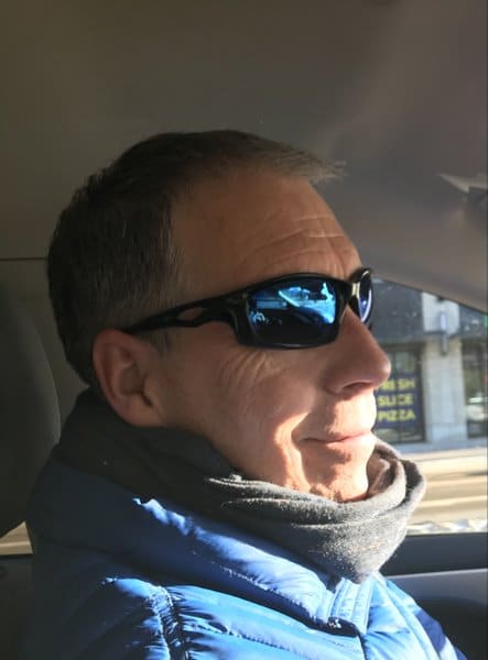 A man with sunglasses sitting in the back of a car.