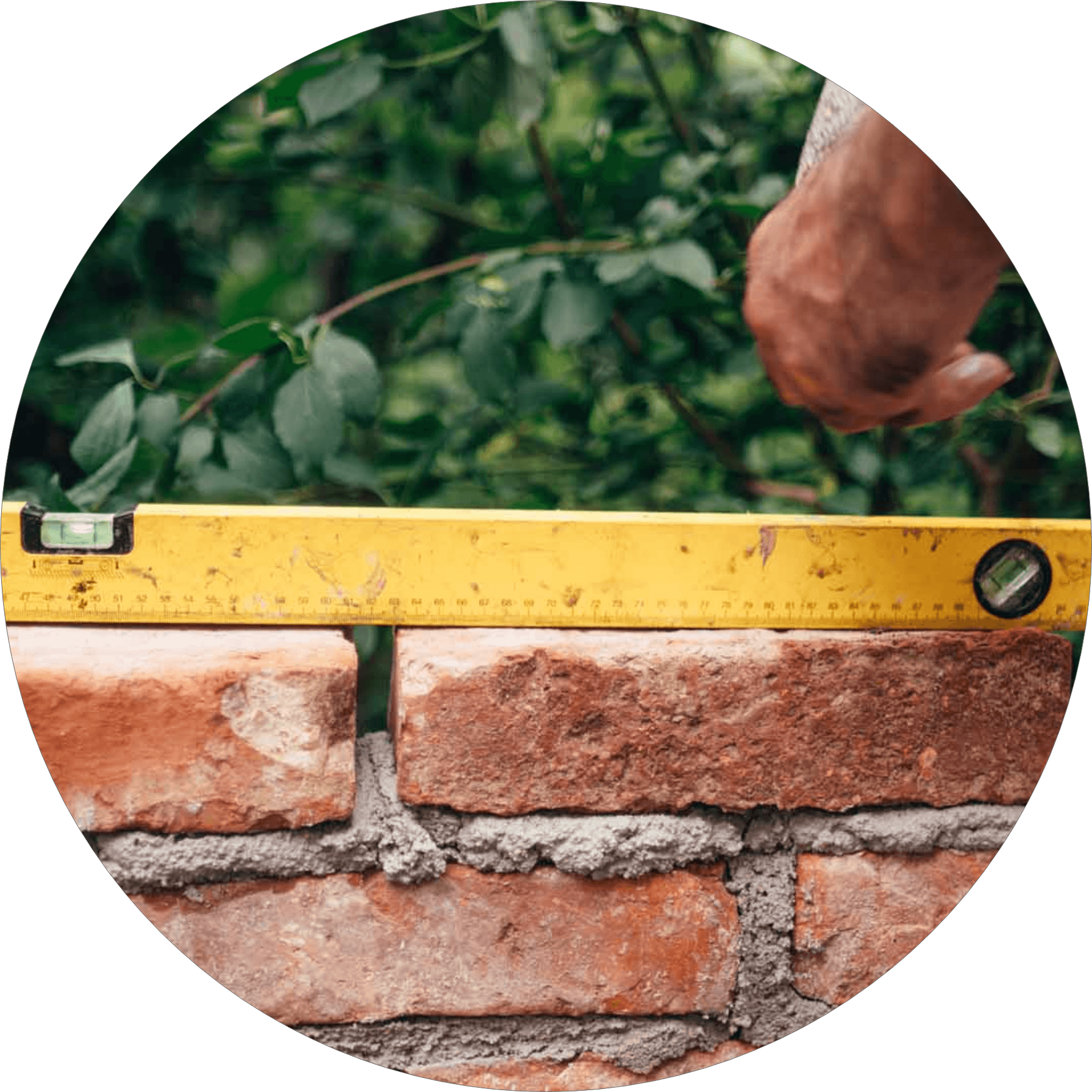 A hand holding a ruler over a brick wall.