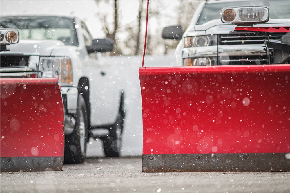 A red truck with snow on it and cars behind