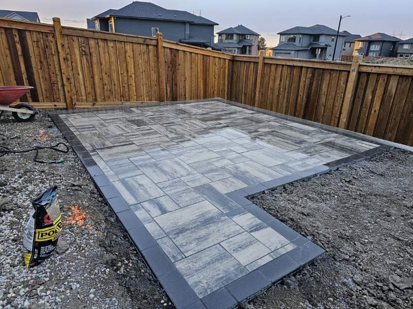 A patio with a concrete block floor and wood fence.