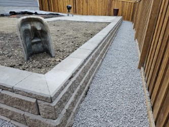 A backyard with gravel and concrete walls